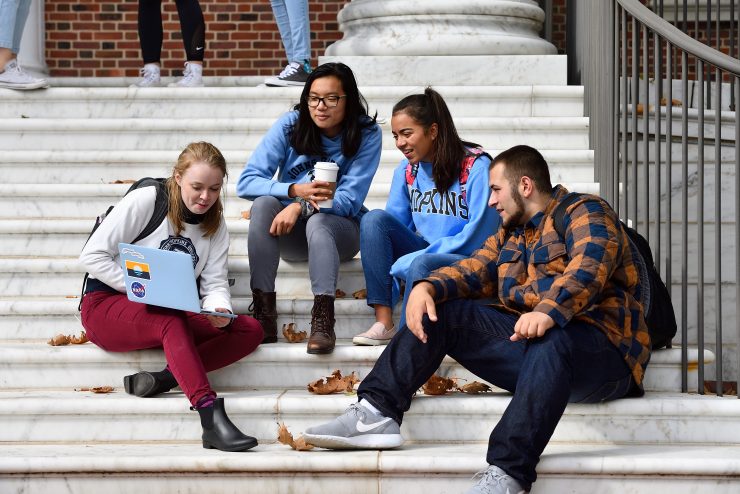 Group of students sitting on stairs on Homewood campus.