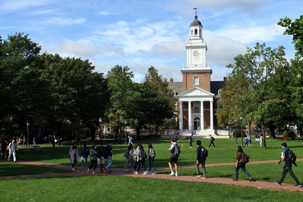 Photo of people walking through quad outside JHU's Gilman Hall.
